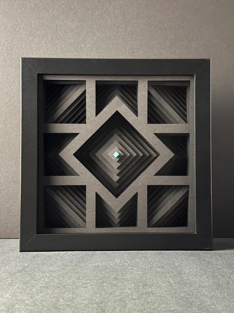 NF-02, a dark framed paper relief with nested diamond layers and a pale cyan center.